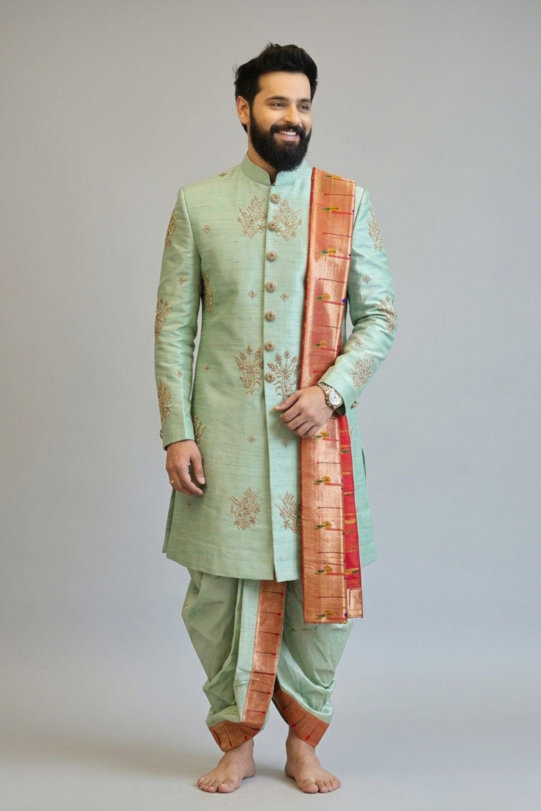 Man wearing a light green sherwani with a red and gold dupatta on a plain background