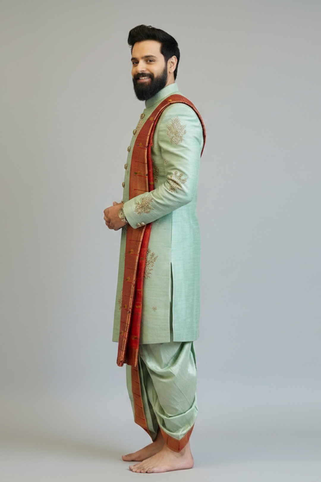 Man wearing a traditional light green sherwani with a red dupatta on a plain background