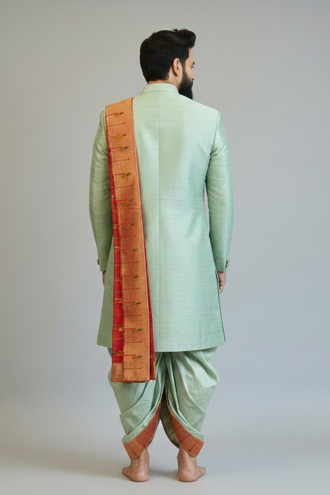 Man wearing a light green sherwani with a red and gold dupatta on a plain background