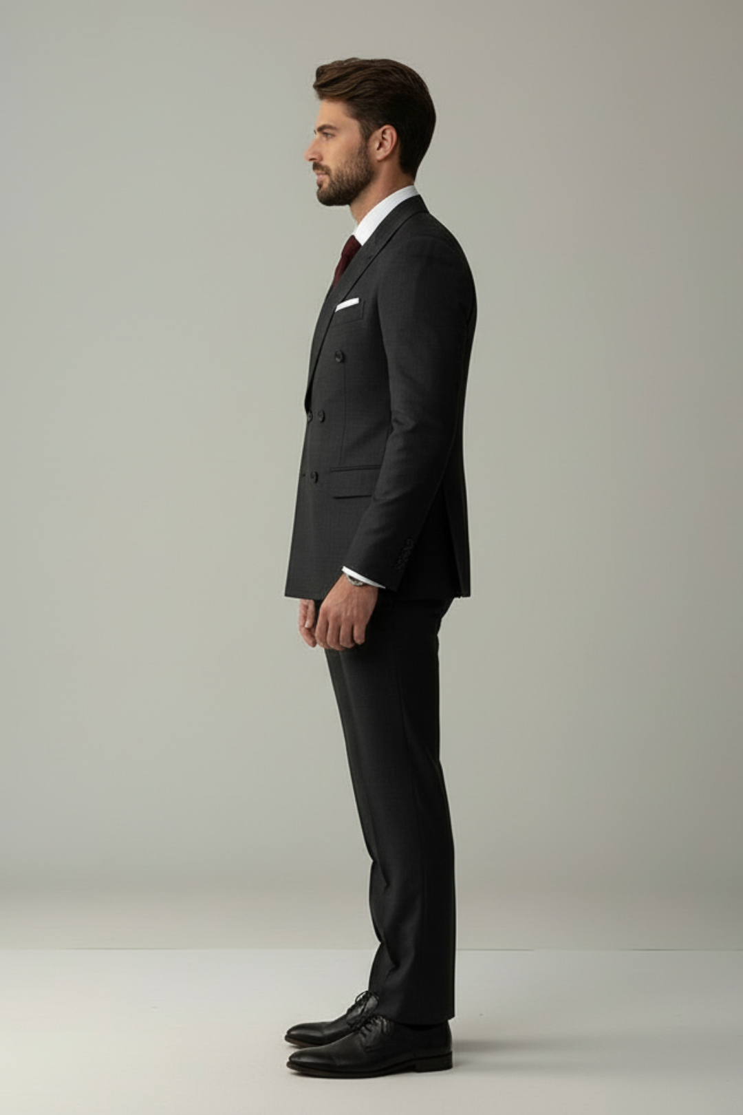 Man wearing a black suit standing against a plain background