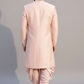 Man wearing a light pink traditional outfit on a plain background