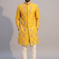 Man wearing a yellow embroidered sherwani with white pants on a gray background