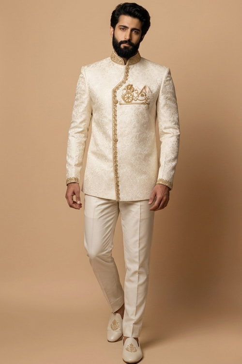 Man wearing a traditional cream sherwani with gold embroidery on a beige background