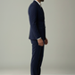 Man wearing a navy suit and brown shoes on a plain background