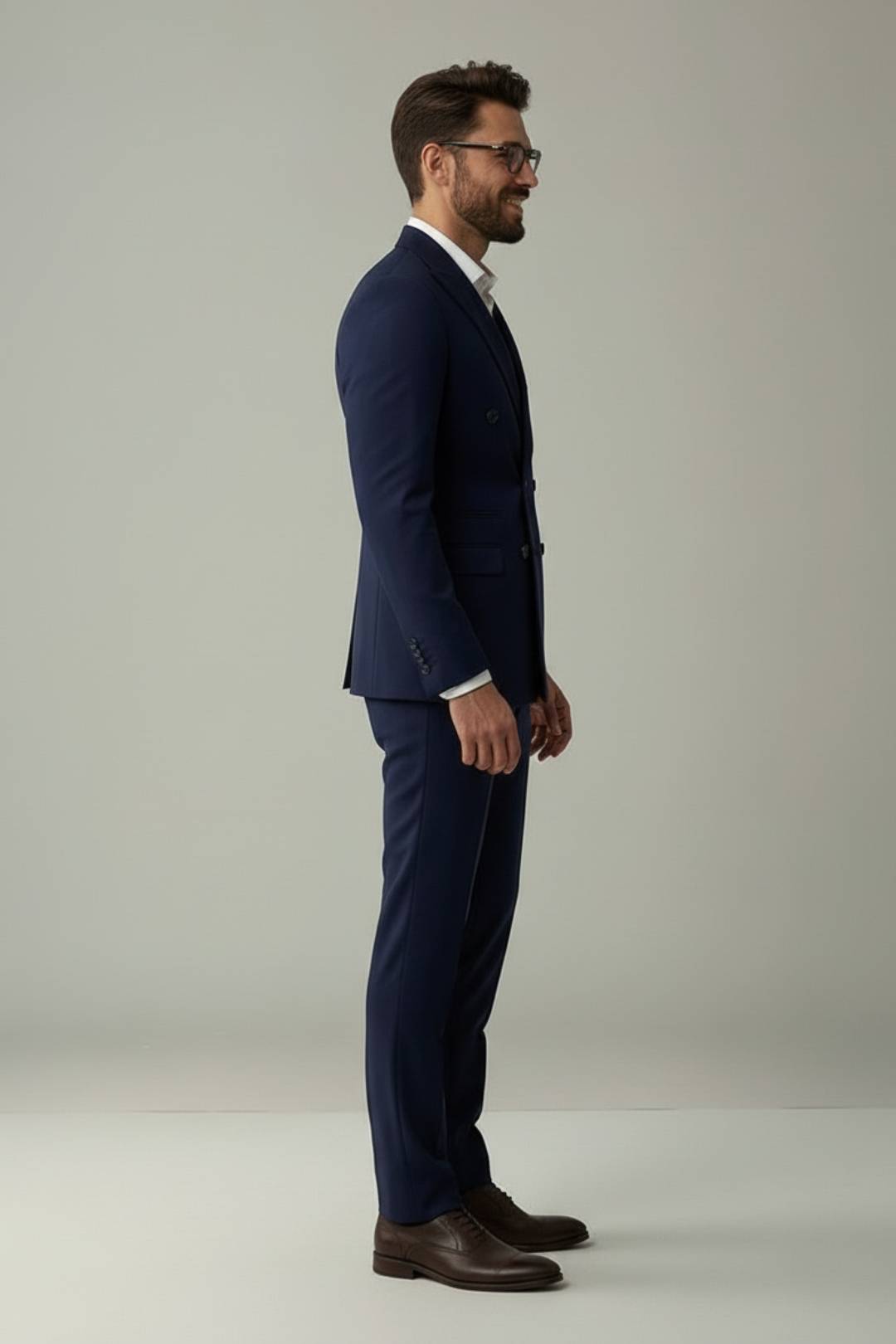 Man wearing a navy suit and brown shoes on a plain background
