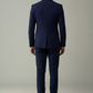 Man wearing a navy blue suit standing against a plain background