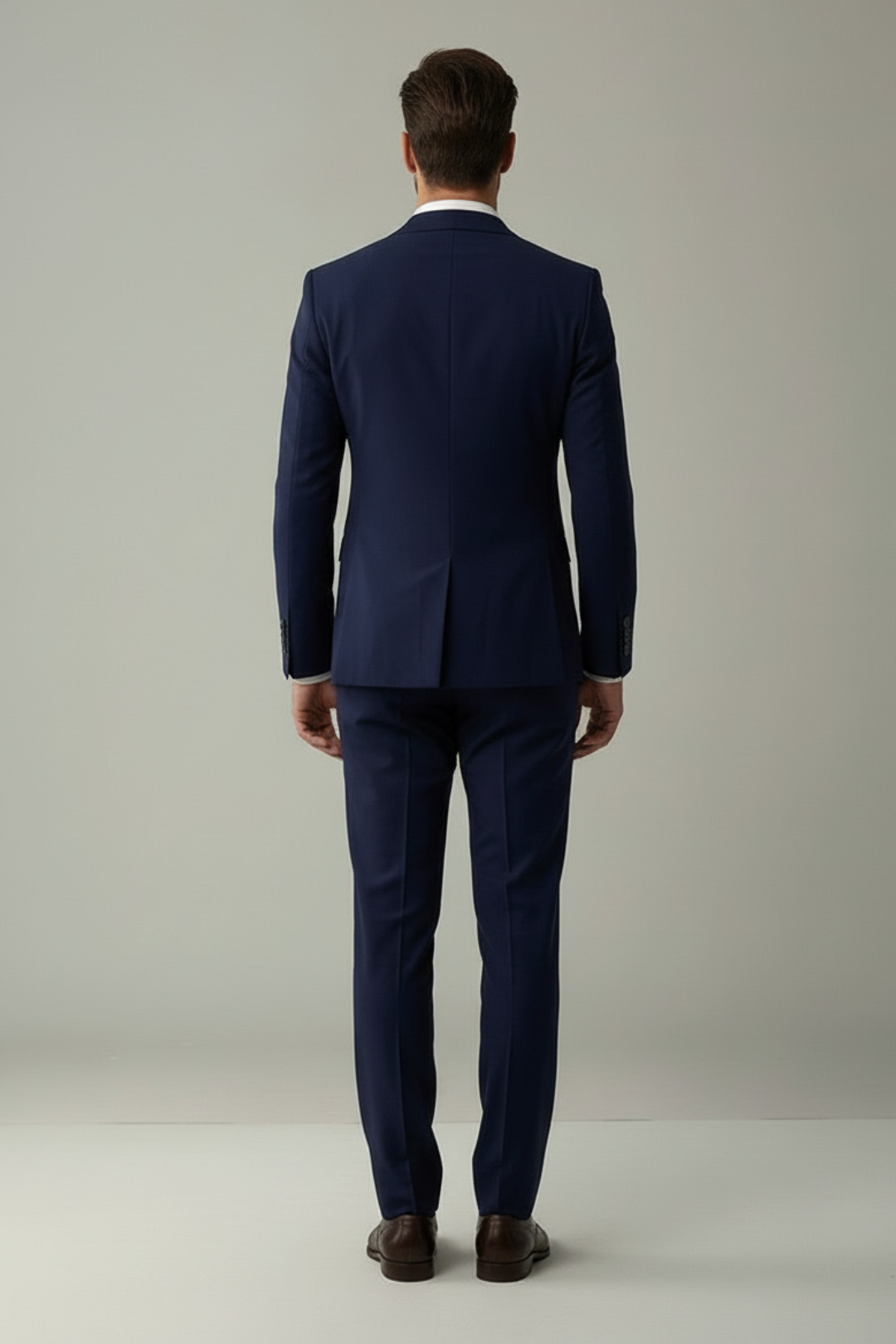 Man wearing a navy blue suit standing against a plain background