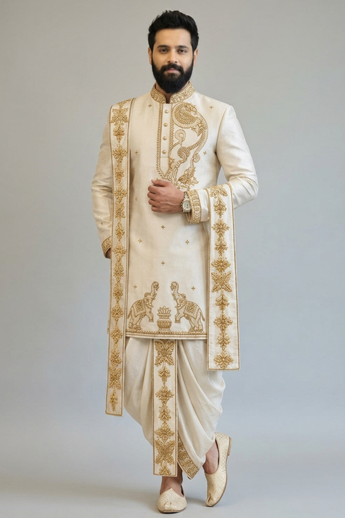 Man wearing a traditional embroidered sherwani against a plain background