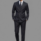 Man wearing a black suit and sunglasses on a gray background