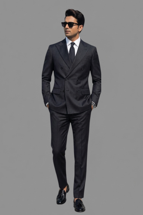 Man wearing a black suit and sunglasses on a gray background