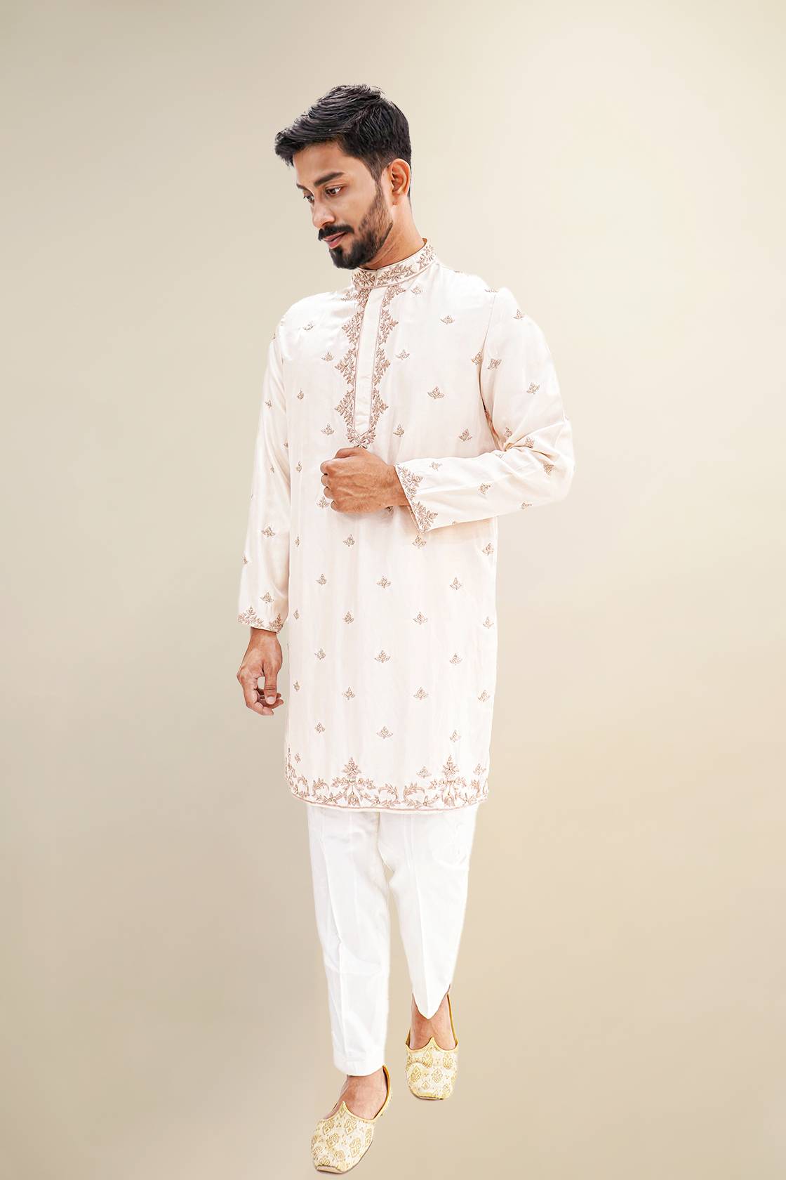 A man wearing a rose pink habutai kurta with zardozi butta work, standing with a smile.