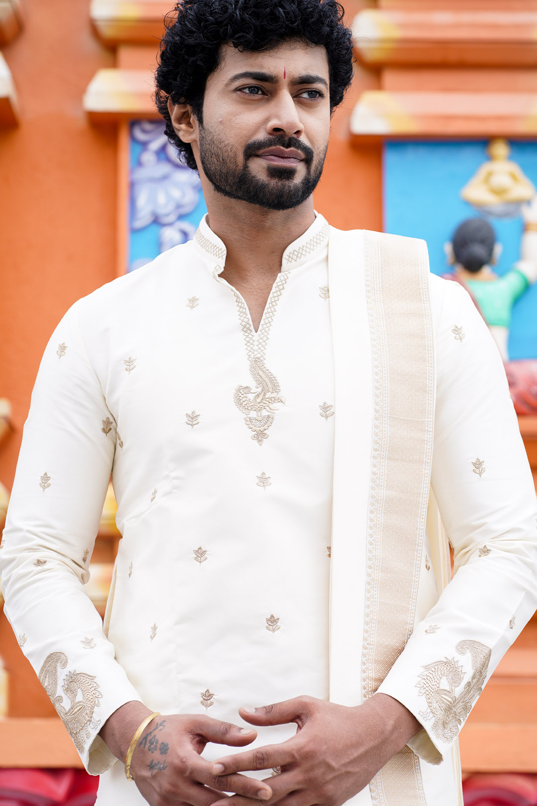Man wearing a white embroidered kurta with a colorful background
