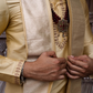 Close-up of a person wearing a traditional beige outfit with intricate details.