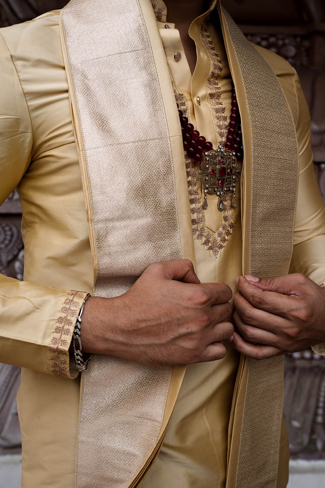 Close-up of a person wearing a traditional beige outfit with intricate details.