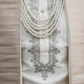 Close-up of a white embroidered garment with pearl necklaces on a beige background