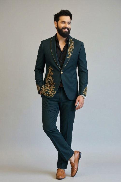 Man wearing a dark green suit with gold embroidery on a plain background