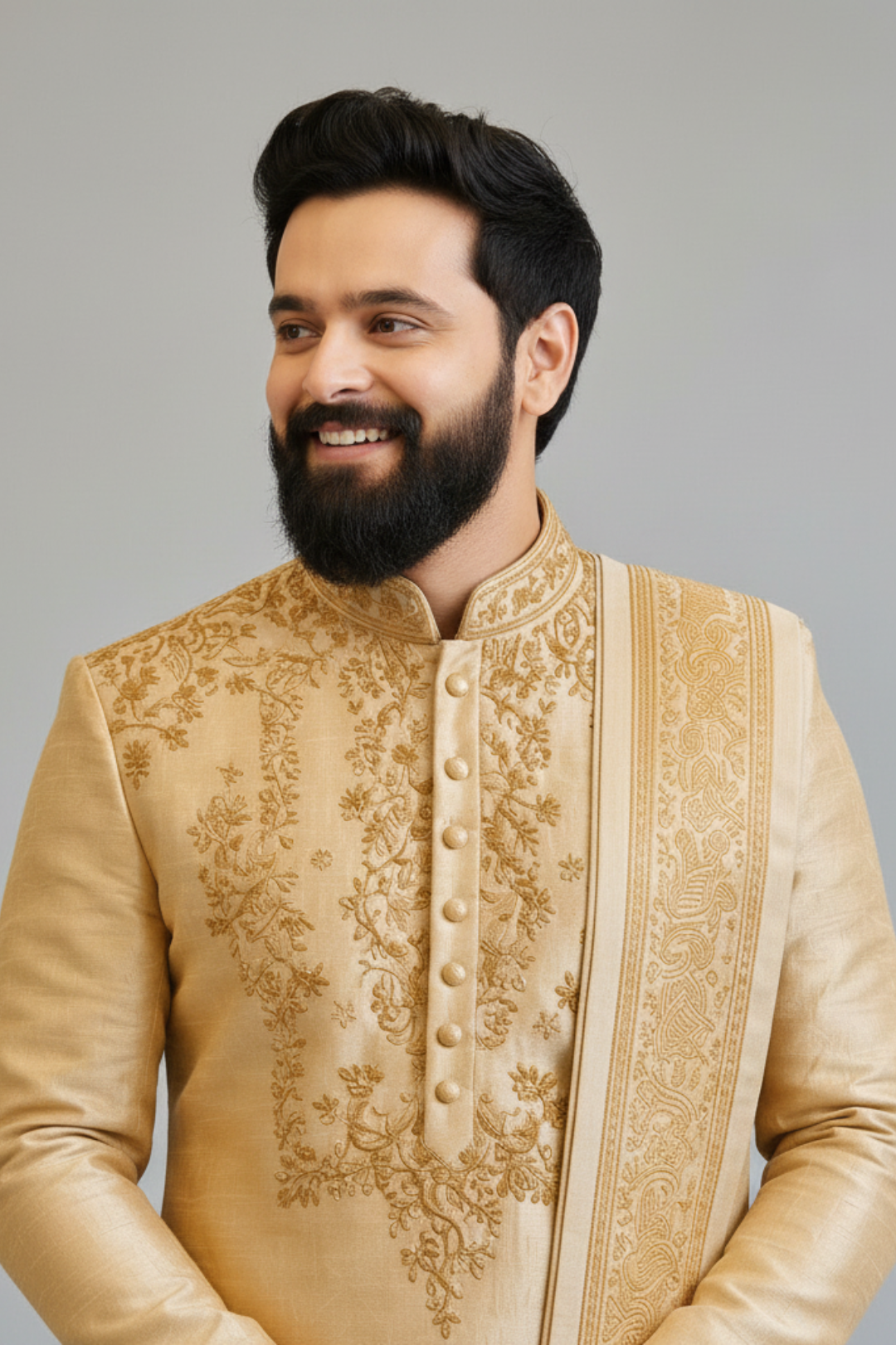 Man wearing a traditional embroidered beige sherwani against a gray background
