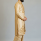 Man wearing a traditional beige sherwani with intricate embroidery on a plain background