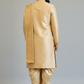 Man wearing a traditional beige sherwani against a plain background