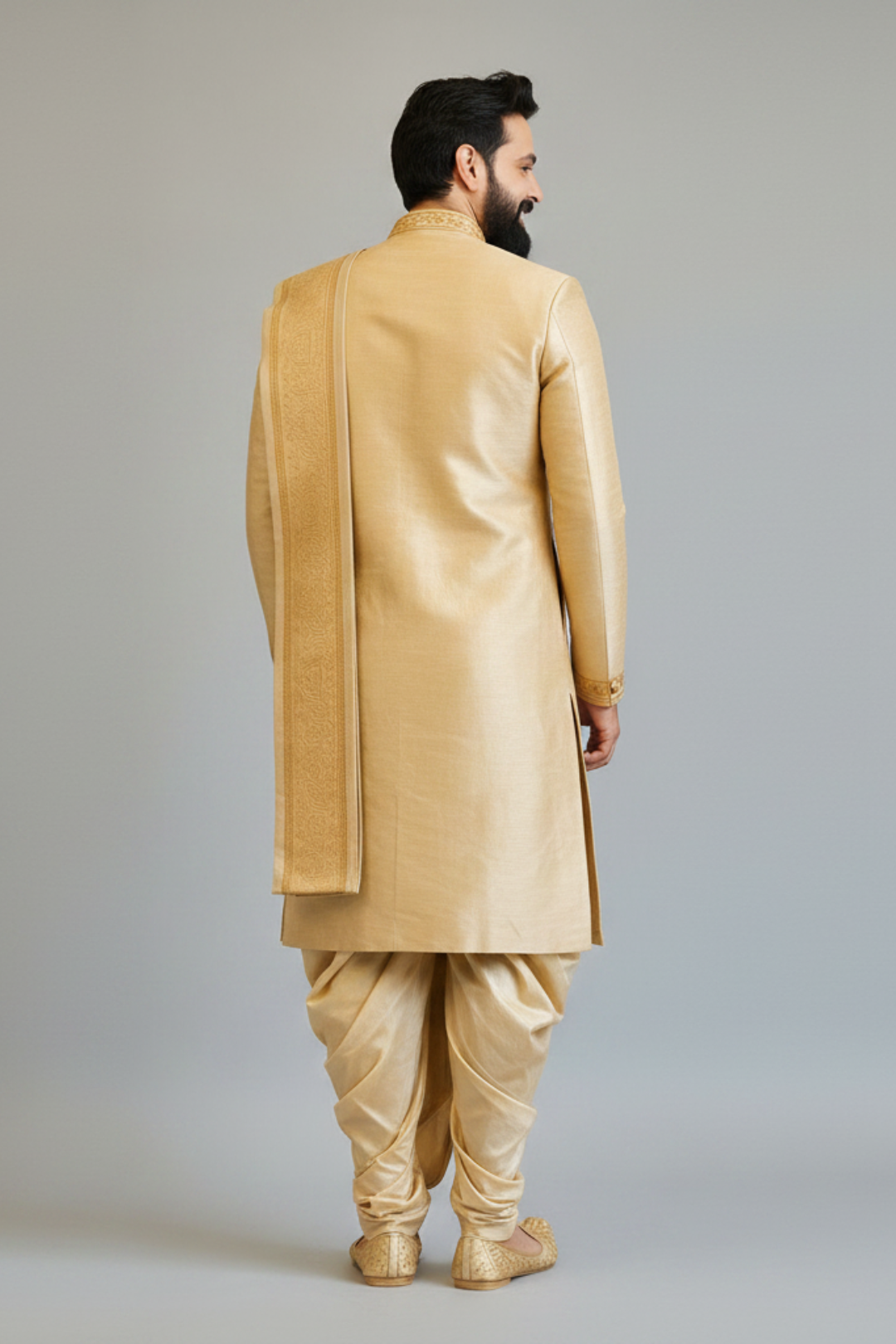 Man wearing a traditional beige sherwani against a plain background