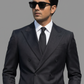 Man wearing a black suit and sunglasses against a gray background