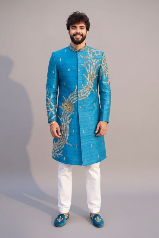 Man wearing a blue embroidered sherwani with white pants on a gray background