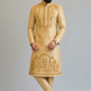 Man wearing a gold embroidered kurta with pants on a gray background