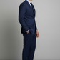 Man wearing a navy blue suit standing against a gray background