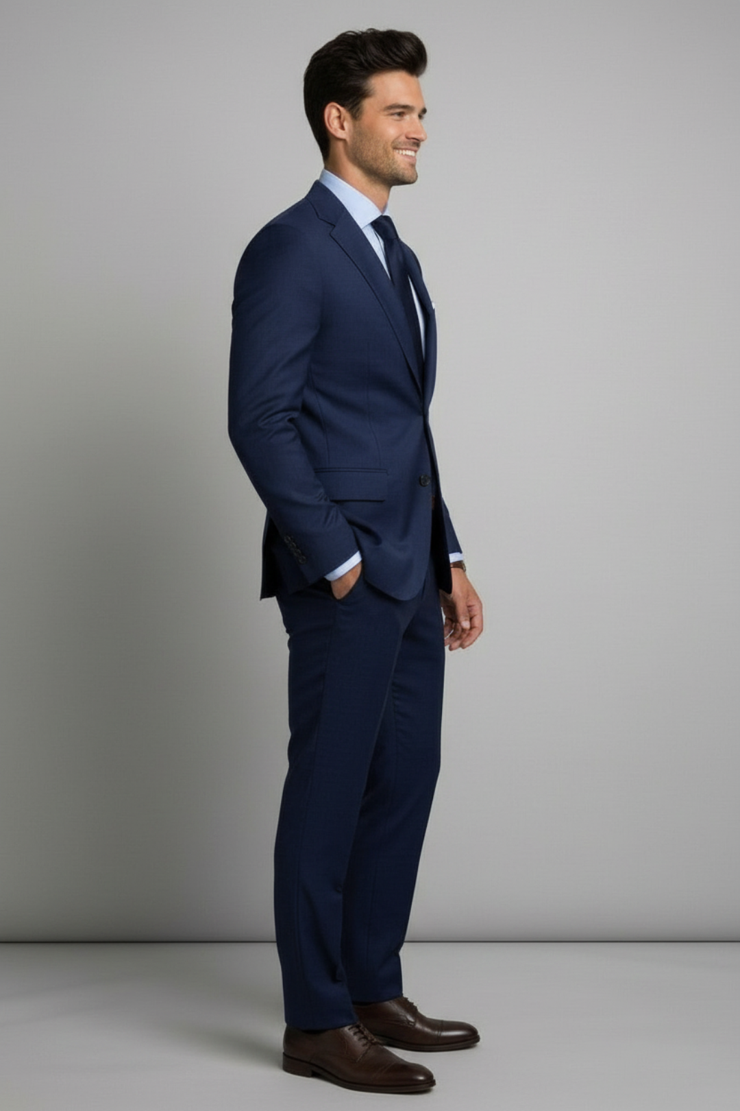 Man wearing a navy blue suit standing against a gray background
