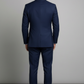 Man wearing a blue suit standing against a plain background