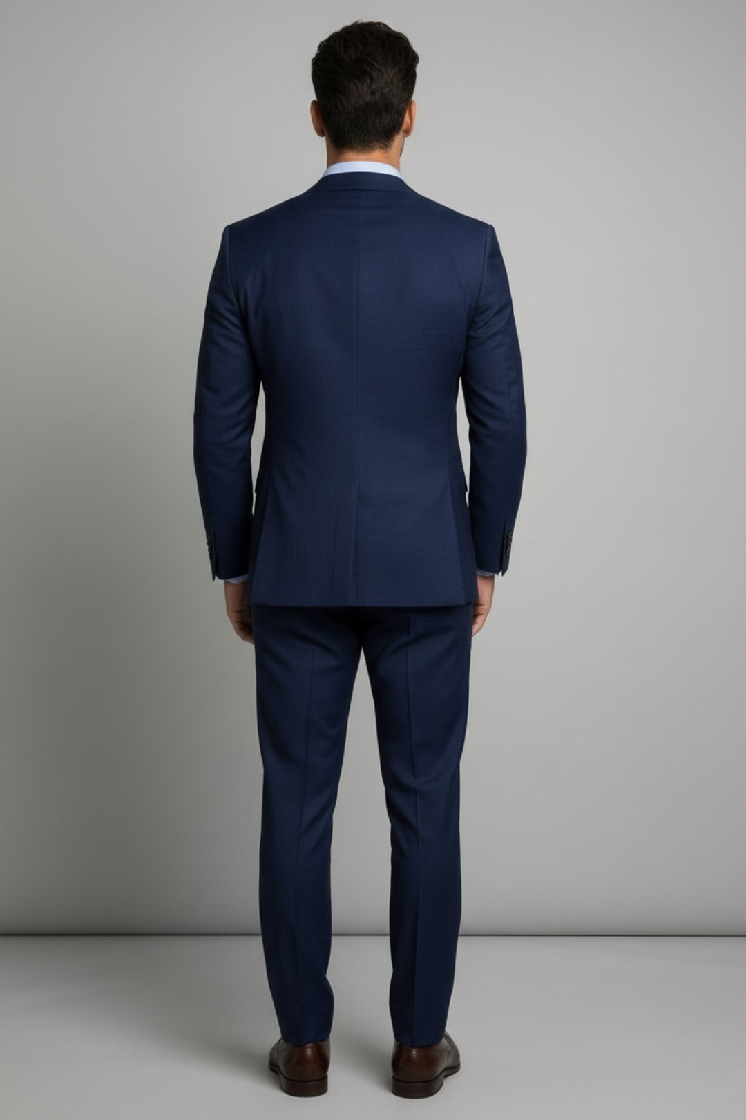 Man wearing a blue suit standing against a plain background