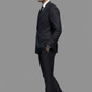Man wearing a black suit and sunglasses on a gray background