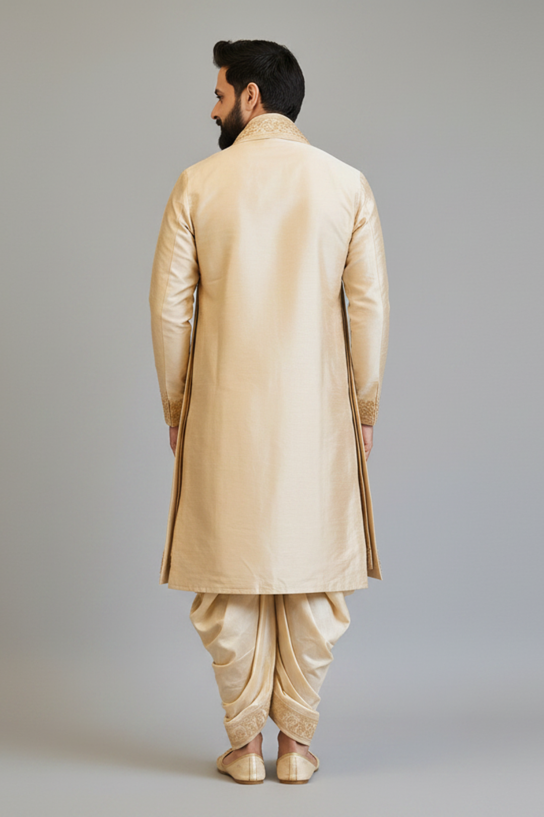 Man wearing a beige sherwani with dhoti on a plain background