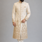 Man wearing a cream embroidered sherwani on a gray background