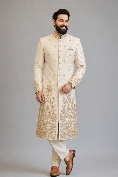 Man wearing a cream embroidered sherwani on a gray background