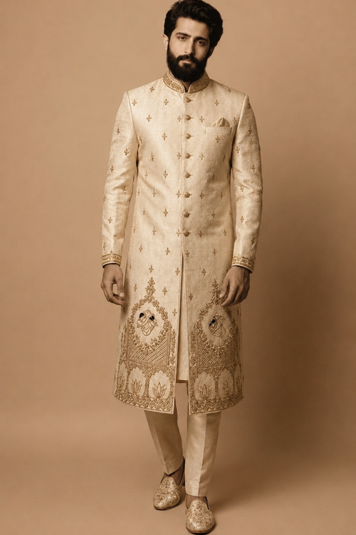 Man wearing a traditional embroidered sherwani against a beige background