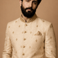 Man wearing a cream embroidered sherwani against a beige background