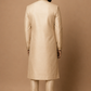 Man wearing a beige sherwani against a brown background