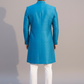 Man wearing a blue sherwani with white pants against a gray background