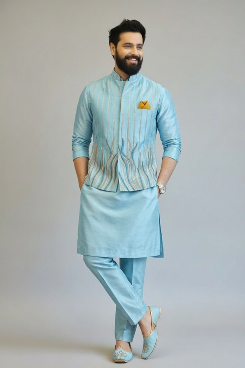 Man wearing a light blue traditional outfit with a plain background