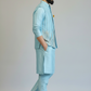 Man wearing a light blue traditional outfit with a plain background