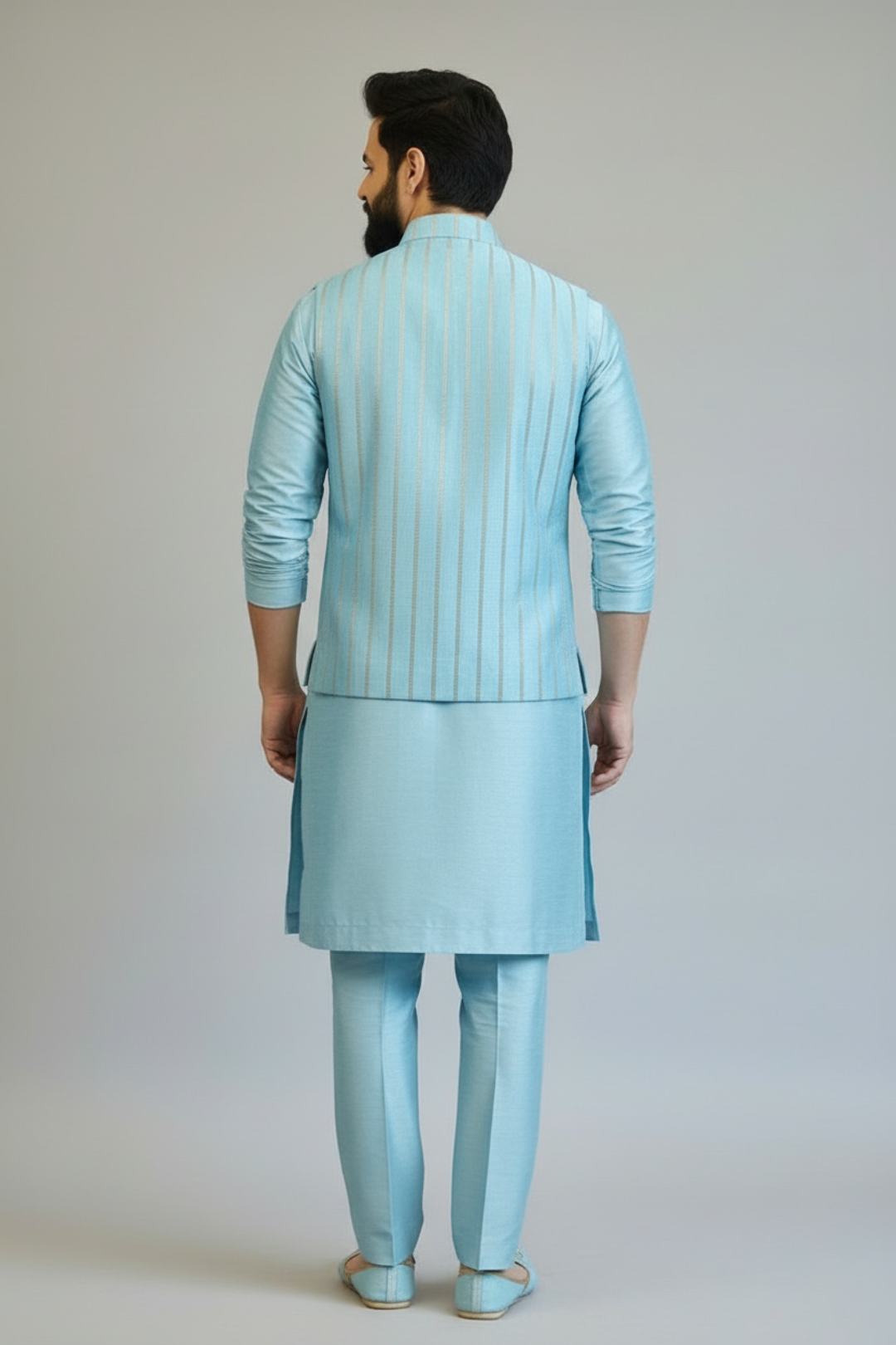 Man wearing a light blue traditional outfit on a plain background