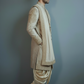 Man wearing a traditional beige sherwani against a plain background