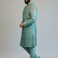 Man wearing a teal sherwani with intricate embroidery on a plain background