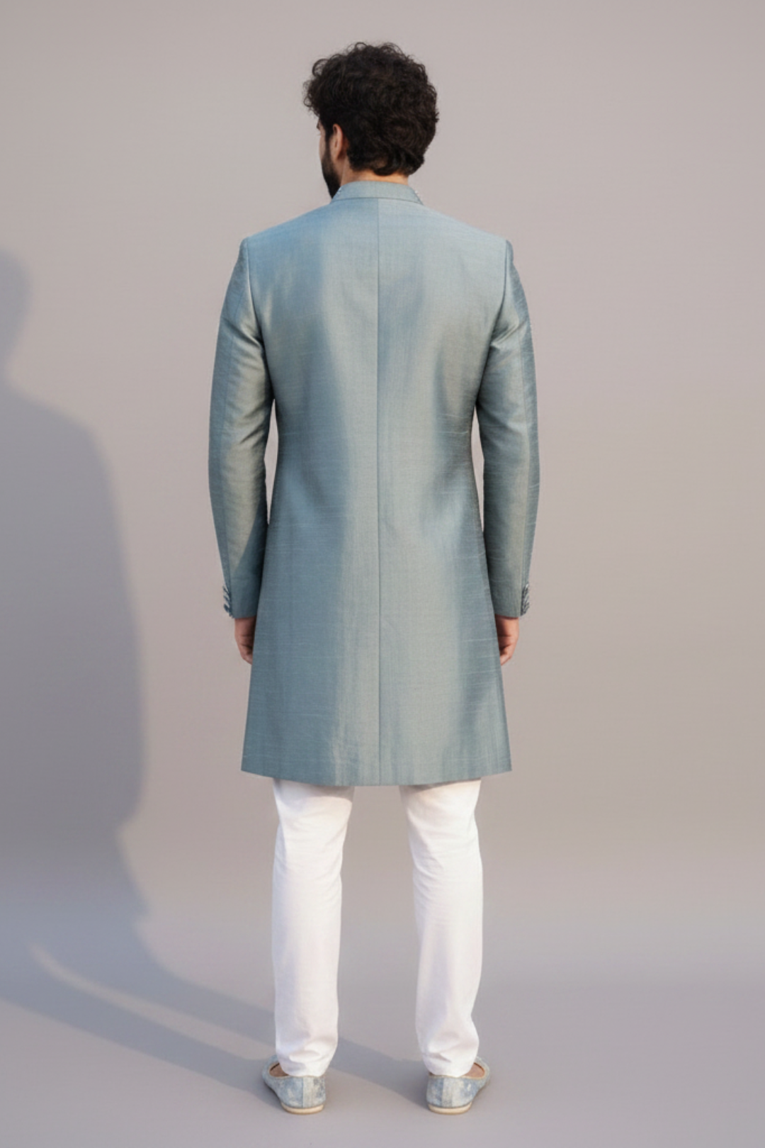 Man wearing a light blue sherwani with white pants on a gray background