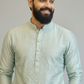 Man wearing a light green embroidered kurta against a plain background
