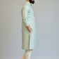 Man wearing a light green kurta with white pants and brown shoes on a plain background