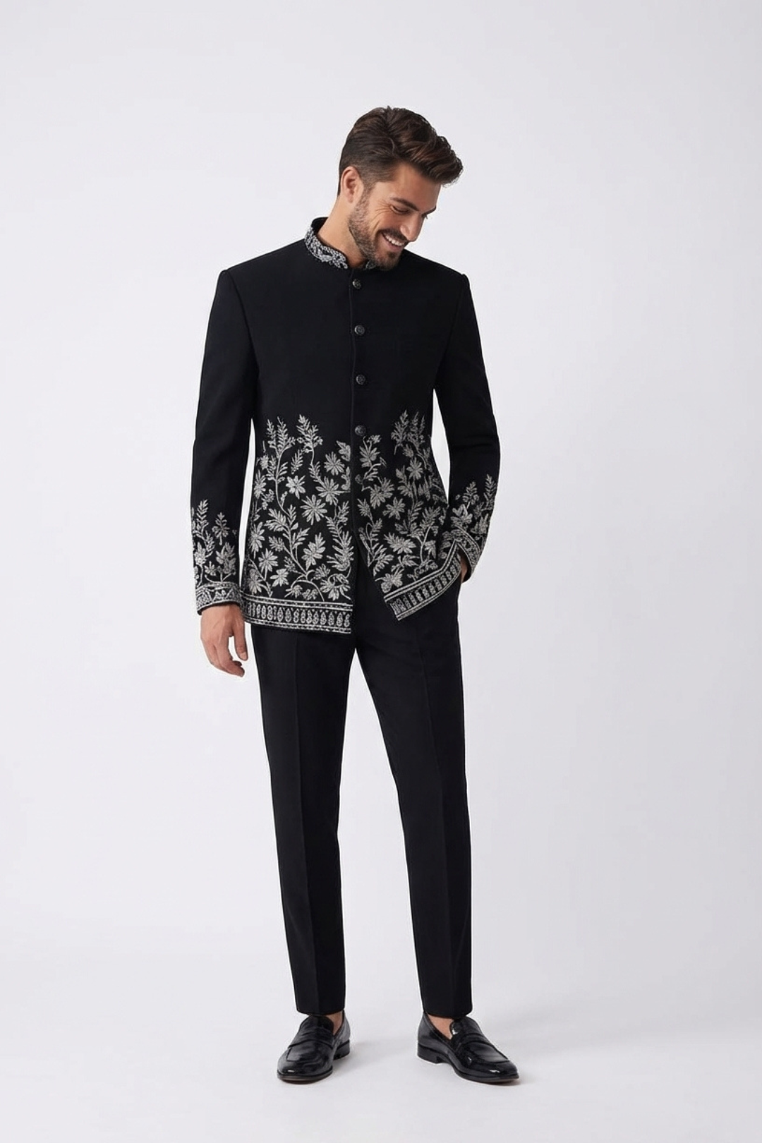 Man wearing a black embroidered jacket and pants on a white background