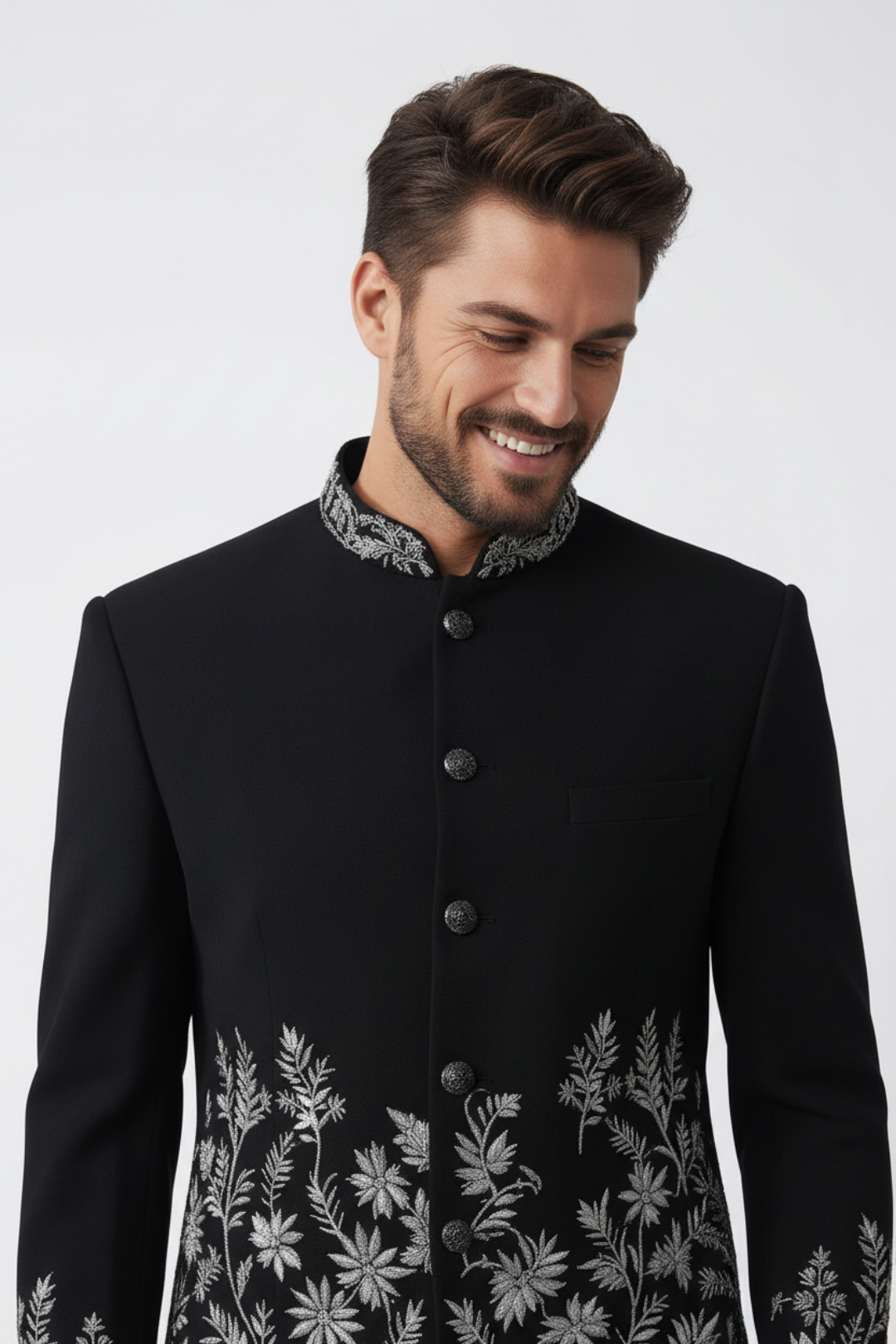 Man wearing a black coat with floral embroidery on a white background
