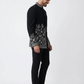 Man wearing a black embroidered jacket and black pants on a white background